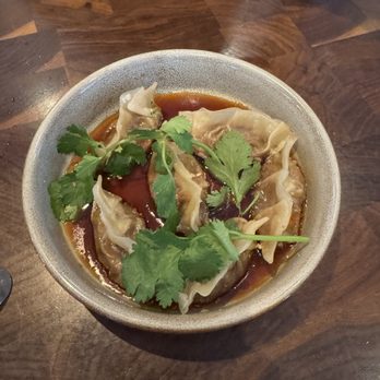 The Henry - Short Rib Potstickers - Dumplings served in a bowl with soy sauce and garnished with fresh cilantro, placed on a wooden table. - New American Near Me - Phoenix, Arizona