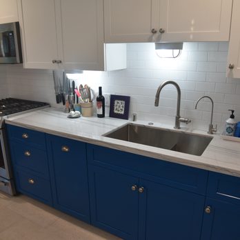 Waters Edge Construction - a kitchen with blue cabinets and white countertops - General Contractors Near Me
