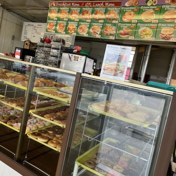 405 Donut - Great options - A glass display case contains assorted baked goods such as donuts and pastries, with a menu board above listing breakfast and lunch options. - Donuts Near Me - Orange, California