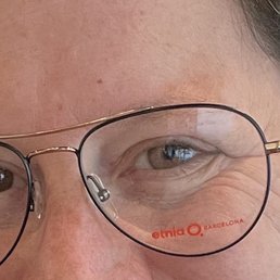 The image shows a close-up of a person's face, highlighting their eye and the eyeglasses they are wearing. The glasses have a thin metal frame, and the lens displays the Etnia Barcelona logo. The person's skin and eye details are visible, with some wrinkles and natural skin texture. The background is not visible, emphasizing the facial features and eyewear.