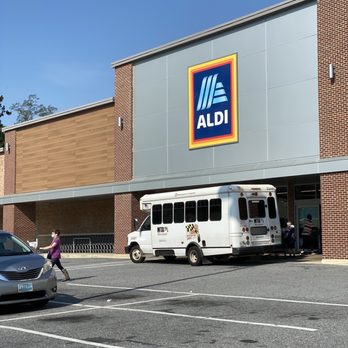 ALDI - a woman crossing the street in front of a aldi store - Grocery Near Me - Reisterstown, Maryland