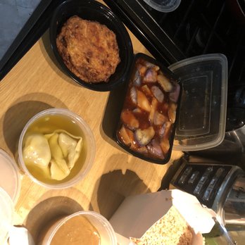 China King - Assorted Asian takeout dishes are displayed on a wooden table, including fried chicken, dumplings in broth, marinated vegetables, and rice. - Chinese Near Me - Merrick, New York