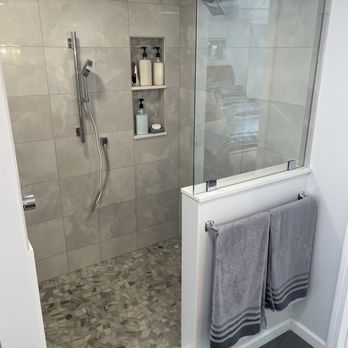 Ramshorn Companies, Inc. - Custom large format tile shower with a half wall, featuring a natural stone floor, quartz threshold, shelves, and a niche. - General Contractors Near Me - Millbury, Massachusetts Ramshorn Companies, Inc. - Custom large format tile shower with a half wall, featuring a natural stone floor, quartz threshold, shelves, and a niche. - General Contractors Near Me - Millbury, Massachusetts