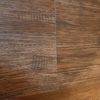 Ed's Floor & Home - Raised plank - Close-up of a wooden floor showing a raised plank with a visible seam and wood grain pattern. - Carpeting Near Me - Plaistow, New Hampshire