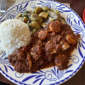 Picante - Shrimp Diablos Plate - A ceramic plate with blue decorative patterns holds a serving of white rice, shrimp diablo in a red spicy sauce, and roasted zucchini and squash with herbs. The dish is set on a wooden table with a fork and napkin nearby, indicating a meal at a Mexican restaurant. - Mexican Near Me - Berkeley, California