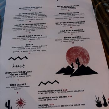 The Moonstone - Menu - A menu from The Moonstone rooftop bar in Tucson, AZ, features Southwestern dishes such as guacamole, chicken wings, and shrimp skewers, along with desserts and beverages. The menu includes prices and descriptions of each item, with a desert-themed illustration of cacti, mountains, and a moon. The design incorporates black and red accents, and the menu is printed on white paper. The location details are at the bottom of the menu. - Bars Near Me - Tucson, Arizona