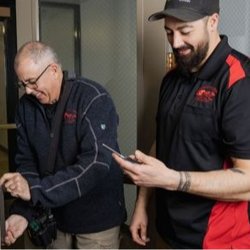 Independent Lock and Parts - Doug McGrail demonstrates rekeying a door lock while son and technician, Quincy, confirms service details on a mobile device....