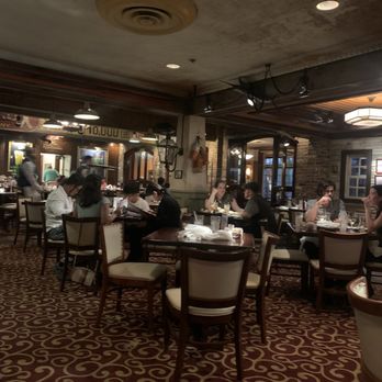 Pappadeaux Seafood Kitchen - Seating - A restaurant interior with several tables occupied by diners, brick walls, and warm lighting, creating a cozy atmosphere. - Seafood Near Me - Albuquerque, New Mexico