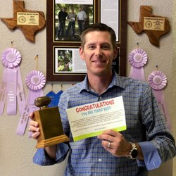38 Pecans - Owner Mark Walls in front of numerous Pecan growing awards receiving an award from HEB!
