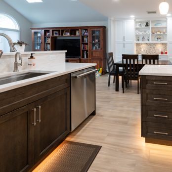 OZ General Contracting - White & wood 2-tone kitchen  L-shaped island, quartz everywhere, custom dining unit + sleek undercab & toe-kick lighting. #DreamKitchen - General Contractors Near Me - Bellmore, New York