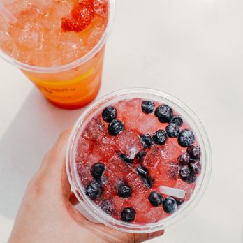 Beyond Juicery + Eatery - a hand holding a plastic cup filled with blueberries and watermelon - Juice Bars & Smoothies Near Me - Ferndale, Michigan