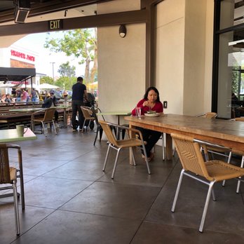 Tender Greens - a woman sitting at a table in a restaurant - New American Near Me - Irvine, California Tender Greens - a woman sitting at a table in a restaurant - New American Near Me - Irvine, California