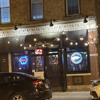 Little Joe's - Bar Front - Nighttime view of Little Joe's bar storefront with string lights, neon signs, and a brick building exterior. - Cocktail Bars Near Me - Chicago, Illinois