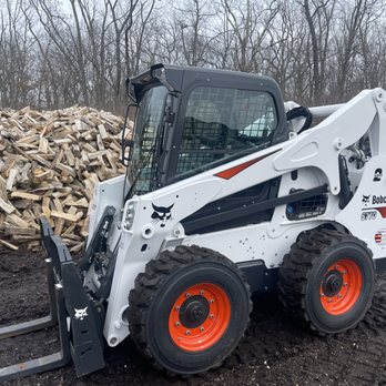 LMB landscaping - a skid steer loader and a pile of wood - Landscaping Near Me