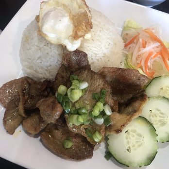 Thaitanic Kitchen - Grilled pork rice plate with egg - A rice plate with a fried egg on top, grilled meat garnished with green onions, and side vegetables including cucumber and shredded carrots. - Thai Near Me - Tempe, Arizona