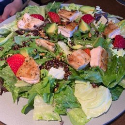 a plate of salad with chicken, avocado, and strawberries