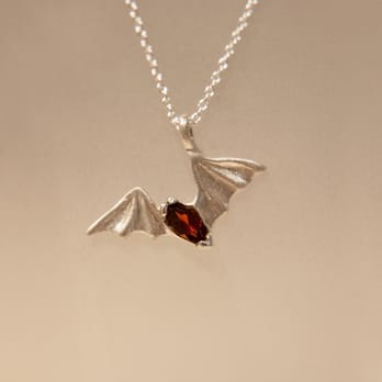 Franzetti Jewelers - Freetail Bat Pendant pictured with a Garnet gemstone. Designer: Franzetti Design - Jewelry Near Me - Austin, Texas Franzetti Jewelers - Freetail Bat Pendant pictured with a Garnet gemstone. Designer: Franzetti Design - Jewelry Near Me - Austin, Texas