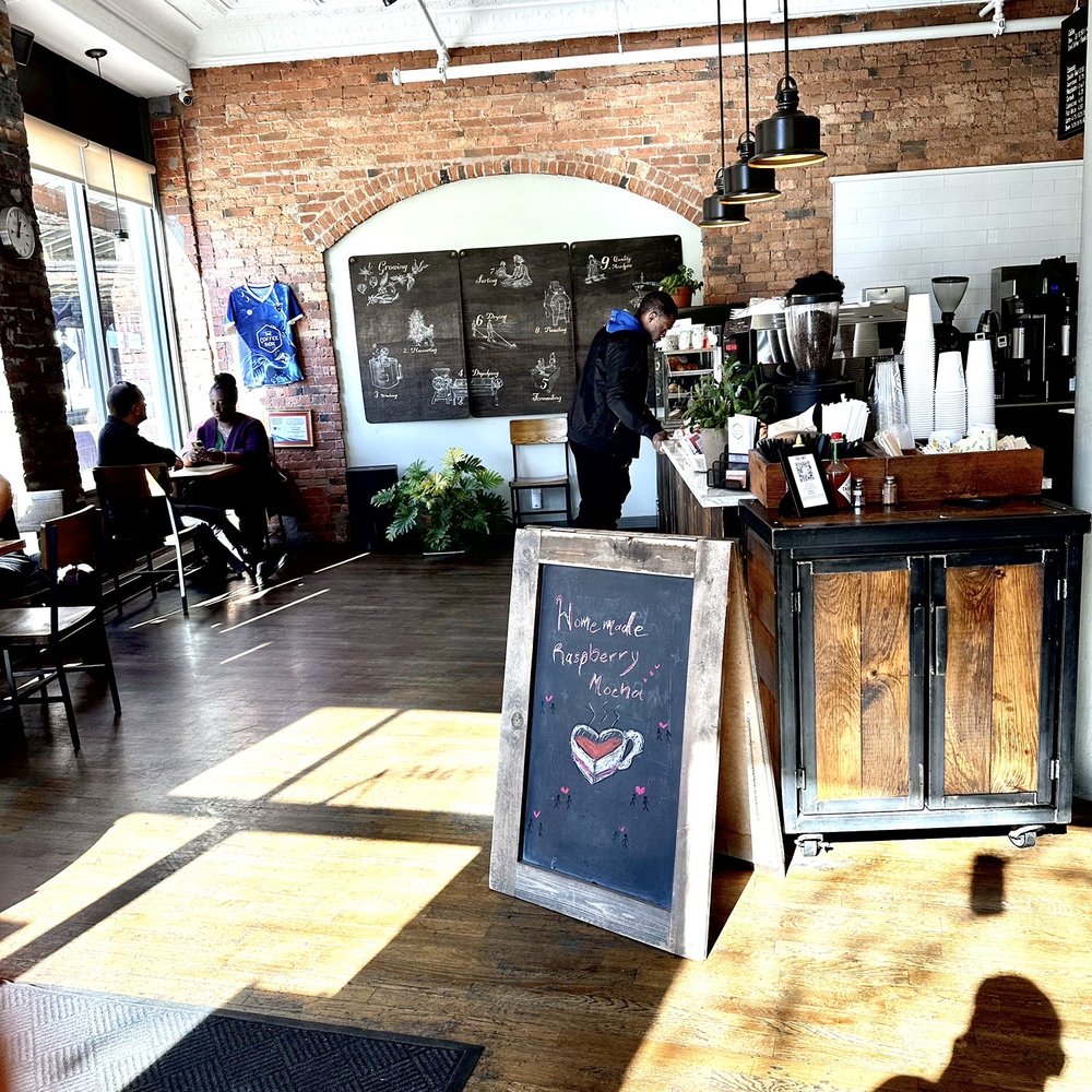 Barista counter and small tables along the entrance. There are more seats on the opposite side as well. Barista counter and small tables along the entrance. There are more seats on the opposite side as well.