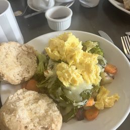 Breakfast bowl with potatoes, veggies, eggs and biscuit on the side.