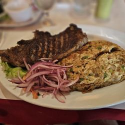 Mistura Peruana - Grilled steak served alongside tacu-tacu (a pan-fried mixture of rice and beans) and topped with sliced red onions.