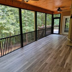 Specialist Aluminum - A black screened pool enclosure surrounds a swimming pool beside a contemporary home, with stone landscaping, patio furniture...