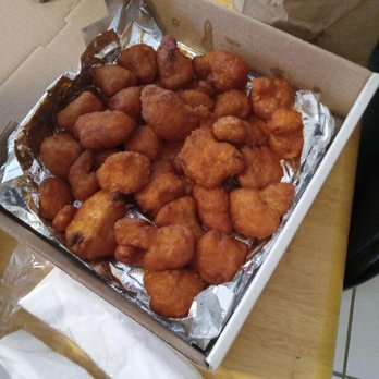 Wingnutz - One pound Cauliflower Nuggiez.  VERY good. - A rectangular cardboard box holds a large quantity of fried chicken nuggets arranged on a foil sheet. The nuggets are golden-brown and appear crispy, filling most of the box. The box is placed on a wooden surface, with part of a white paper bag visible nearby. - Chicken Wings Near Me - Buffalo, New York