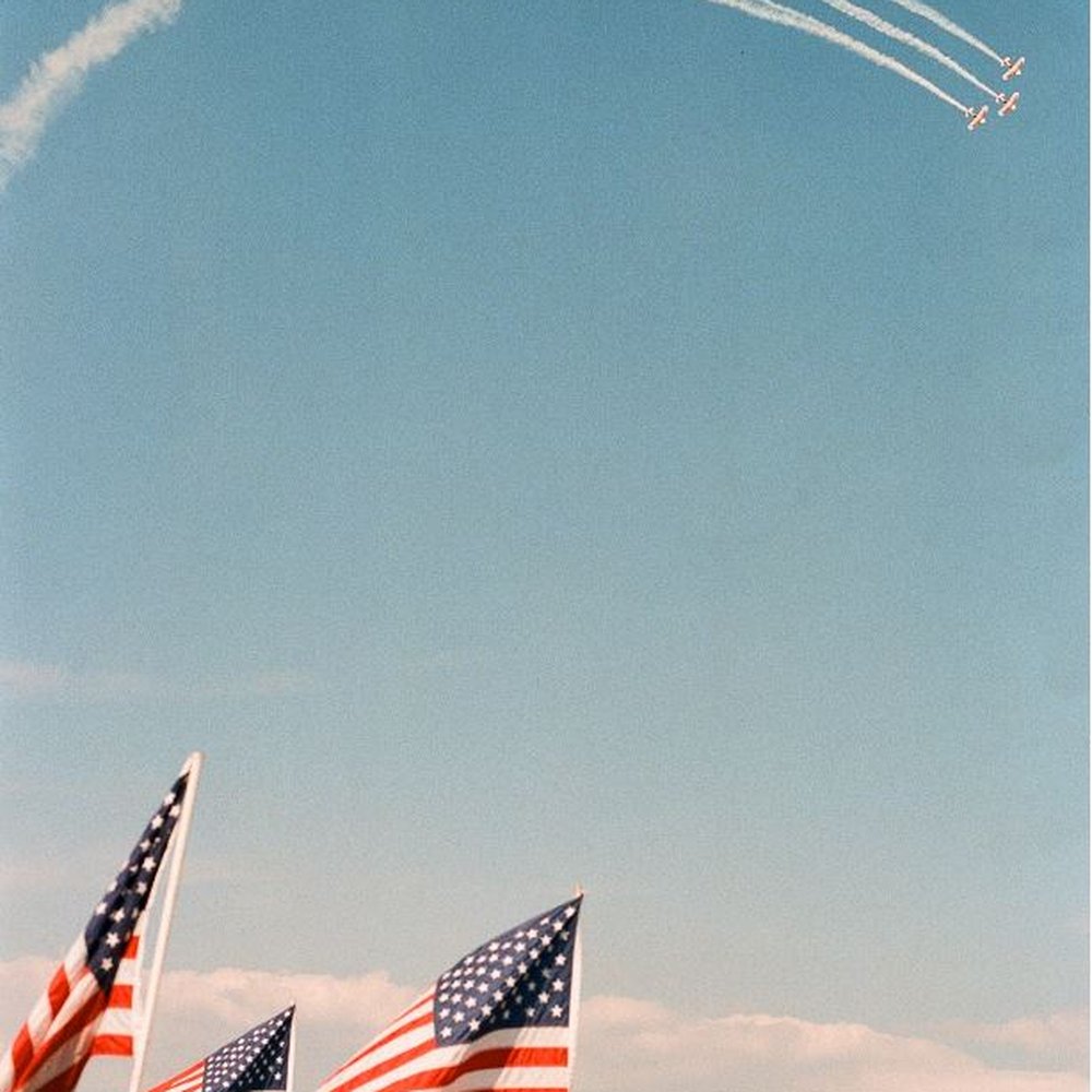 EAA Aviation Museum - Three stripes of white smoke in sky, and red & white stripes on American flags. - Museums Near Me - Oshkosh, Wisconsin EAA Aviation Museum - Three stripes of white smoke in sky, and red & white stripes on American flags. - Museums Near Me - Oshkosh, Wisconsin