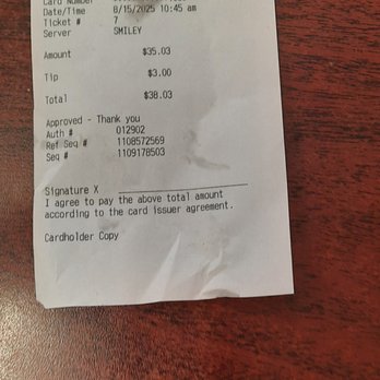 Hambone's Pizza - The image shows a receipt from Hambone's Pizza located at 410 W 17th Street, Cheyenne, WY. The receipt records a purchase totaling $38.03, including a $35.03 pizza and a $3.00 tip. It is dated August 15, 2025, at 10:45 am, with the server listed as SMILEY. The receipt includes authorization and reference numbers, and it is marked as a card transaction. The paper is slightly crumpled and placed on a wooden surface. - Pizza Near Me - Cheyenne, Wyoming