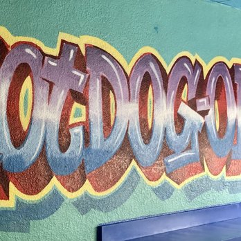 Hotdogopolis - a man sitting in front of a mural - Hot Dogs Near Me - Boca Raton, Florida