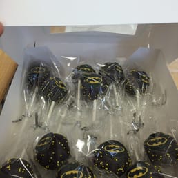 A dozen Batman inspired cake pops with yellow sprinkles. A dozen Batman inspired cake pops with yellow sprinkles.