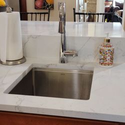 Best Buy Interior Finishes - A better view of the island waterfall and stainless under-mounted prep sink with accessories, cutting board and colander.
