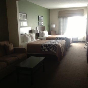 Sleep Inn & Suites - Standing by the bathroom door. That's a couch/sitting area and two queen beds, and TONS of space in between. - Hotels Near Me - Middlesboro, Kentucky Sleep Inn & Suites - Standing by the bathroom door. That's a couch/sitting area and two queen beds, and TONS of space in between. - Hotels Near Me - Middlesboro, Kentucky