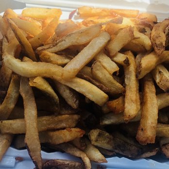 Chaps Pit Beef - Fresh cut fries - A close-up image of a basket containing freshly cooked French fries, with a variety of golden-brown hues and some darker edges. The fries are irregularly shaped, indicating they are hand-cut, and are served in a white basket lined with paper, suggesting a casual dining or takeout setting. - Sandwiches Near Me - Aberdeen, Maryland