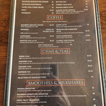 Masuda’s Cafe - The menu displays sections for desserts, coffee, chai & teas, and smoothies & milkshakes. Dessert options include khatayee, namaki, dulce de leche cookies, pistachio shortbread, camel eyes, roht, croissant, and various baked goods and sweets. Coffee options feature gourmet brewed coffee, espresso, cappuccino, matcha tea latte, hot chocolate, and specialty lattes like pistachio and cardamom. Chai & teas include sheers chai, Kashmiri chai, golden chai, saffron tea, and assorted teas. Smoothies and milkshakes include mango, Palawan, dried fruit, and pistachio milkshake, with prices ranging from $4 to $9. The menu notes the use of beans from Rao's Coffee Roasting Co. and provides a reminder to inform the server of food allergies. - Cafes Near Me - Amherst, Massachusetts