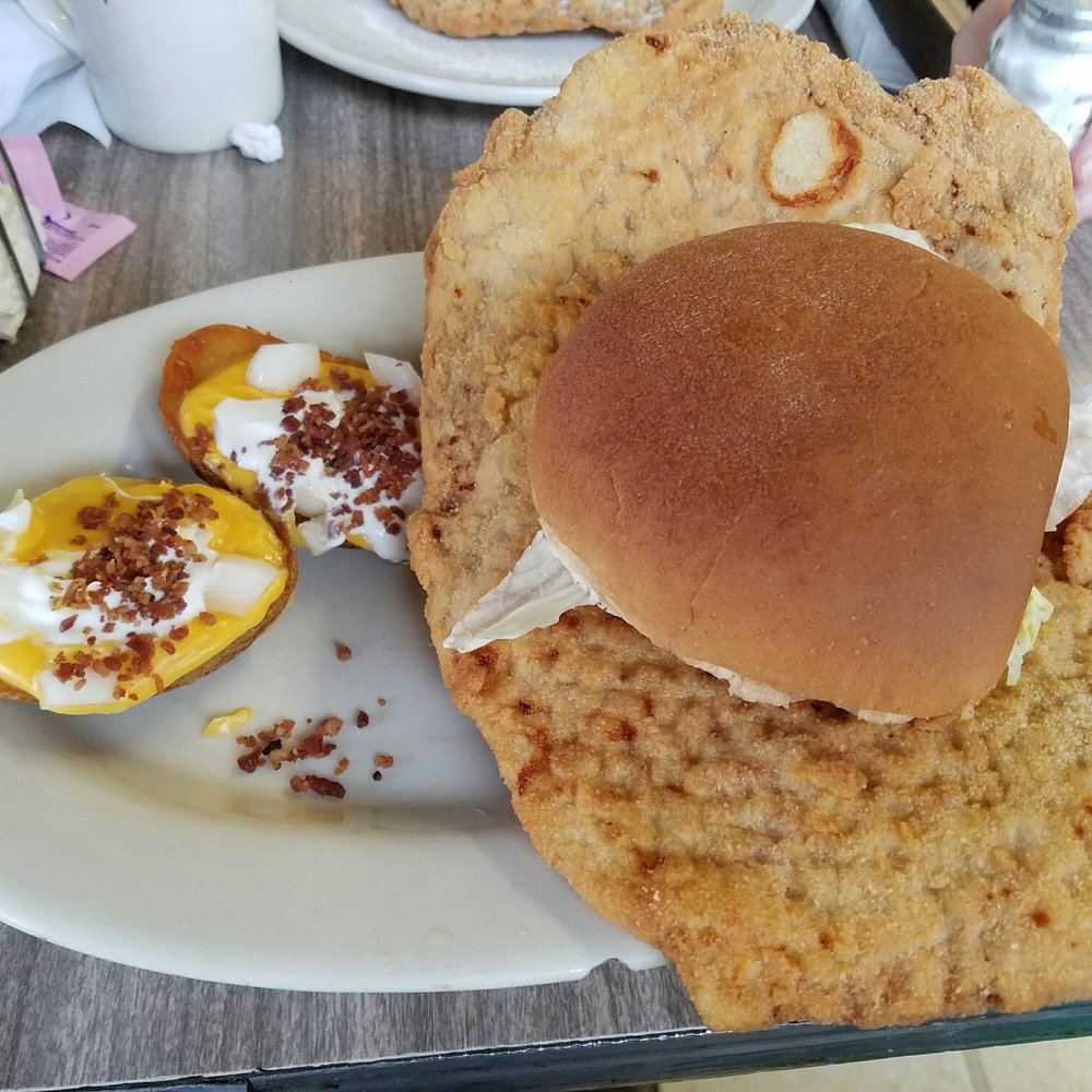 a plate of food including a burger and a baked potato a plate of food including a burger and a baked potato