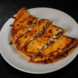 13" flour tortilla loaded with tender birria, melted cheese, fresh onion, and cilantro, grilled to perfection.