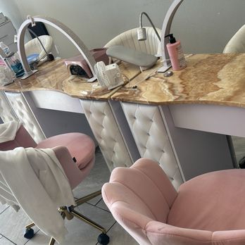 Eastern Spa And Nails - A nail salon workstation features pink upholstered chairs, a marble countertop, and manicure tools including lamps, brushes, and bottles. - Nail Salons Near Me - Albuquerque, New Mexico