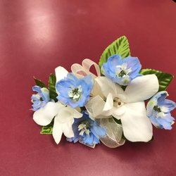 First Colony Florist & Gifts - Elegant white dendrobium orchid and blue delphiniums in a corsage.