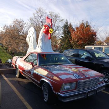 Ron's Roost - A classic car decorated with patriotic themes and a large rooster figure on top is parked in a parking lot, with trees and other vehicles nearby. - Burgers Near Me - Cincinnati, Ohio