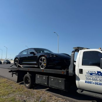 Zain Towing - Black luxury car towed on a flatbed along a highway. - Towing Near Me - New Orleans, Louisiana Zain Towing - Black luxury car towed on a flatbed along a highway. - Towing Near Me - New Orleans, Louisiana