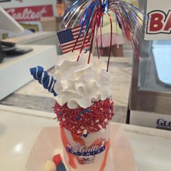 3 Gulls Creamery - 4th of July stuffed shake- vanilla shake with strawberry drizzle, icing and sprinkles on the rim, whipped cream and swirly sucker.