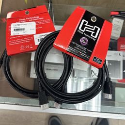 A black high-speed HDMI cable from Hosa Technology is coiled and placed on a glass display counter. The packaging features the Hosa Technology logo and product details, including HDMI specifications. Additional product boxes are visible in the background, indicating a retail environment that sells electronic accessories and cables.