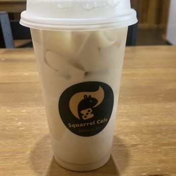 Squarrel Cafe - Earl Grey Latte - A plastic cup filled with an iced drink, topped with a plastic lid and straw, displaying the Squirrel Cafe logo from Brooklyn, NY. - Coffee & Tea Near Me - Brooklyn, New York