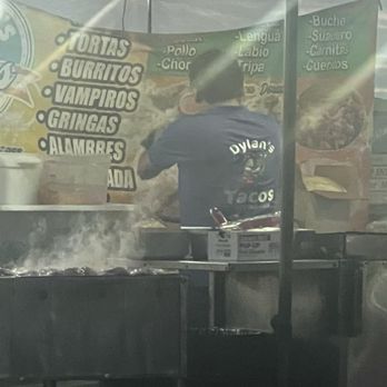 Dylan’s Tacos - One of the workers and their sign with what they offer. - Tacos Near Me - Bakersfield, California Dylan’s Tacos - One of the workers and their sign with what they offer. - Tacos Near Me - Bakersfield, California