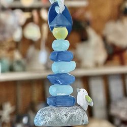 The Sand House - Sea glass lighthouse ornament of stacked blue glass on a gray rock with a small bird