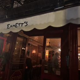 Exterior shot of Emmett's that shows the white awning and cozy, brick wall interior.