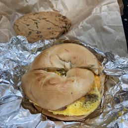 Sausage, egg, and cheese breakfast sandwich on a plain bagel. Chocolate chip cookie.