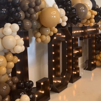 The Loft - Beautiful venue - A decorative display features a large arrangement of balloons in black, white, beige, and gold colors, clustered around illuminated letters spelling 'LOVE'. The balloons vary in size and are arranged to create a festive backdrop, with the letters lit from within, enhancing the visual impact for an event setting. - Venues & Event Spaces Near Me - Long Beach, California