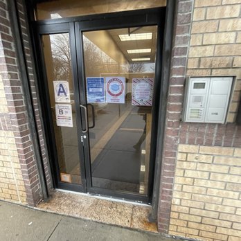 Shipwrecked - The image shows a glass door with COVID-19 safety signs, including mask requirements, at the entrance of a building in an urban area. - Mini Golf Near Me - Brooklyn, New York