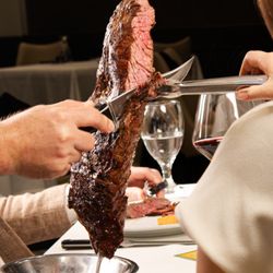 Chama Gaúcha - Houston - A server carves grilled steak directly onto a guest's plate, showcasing the signature tableside service and authentic Brazilian
